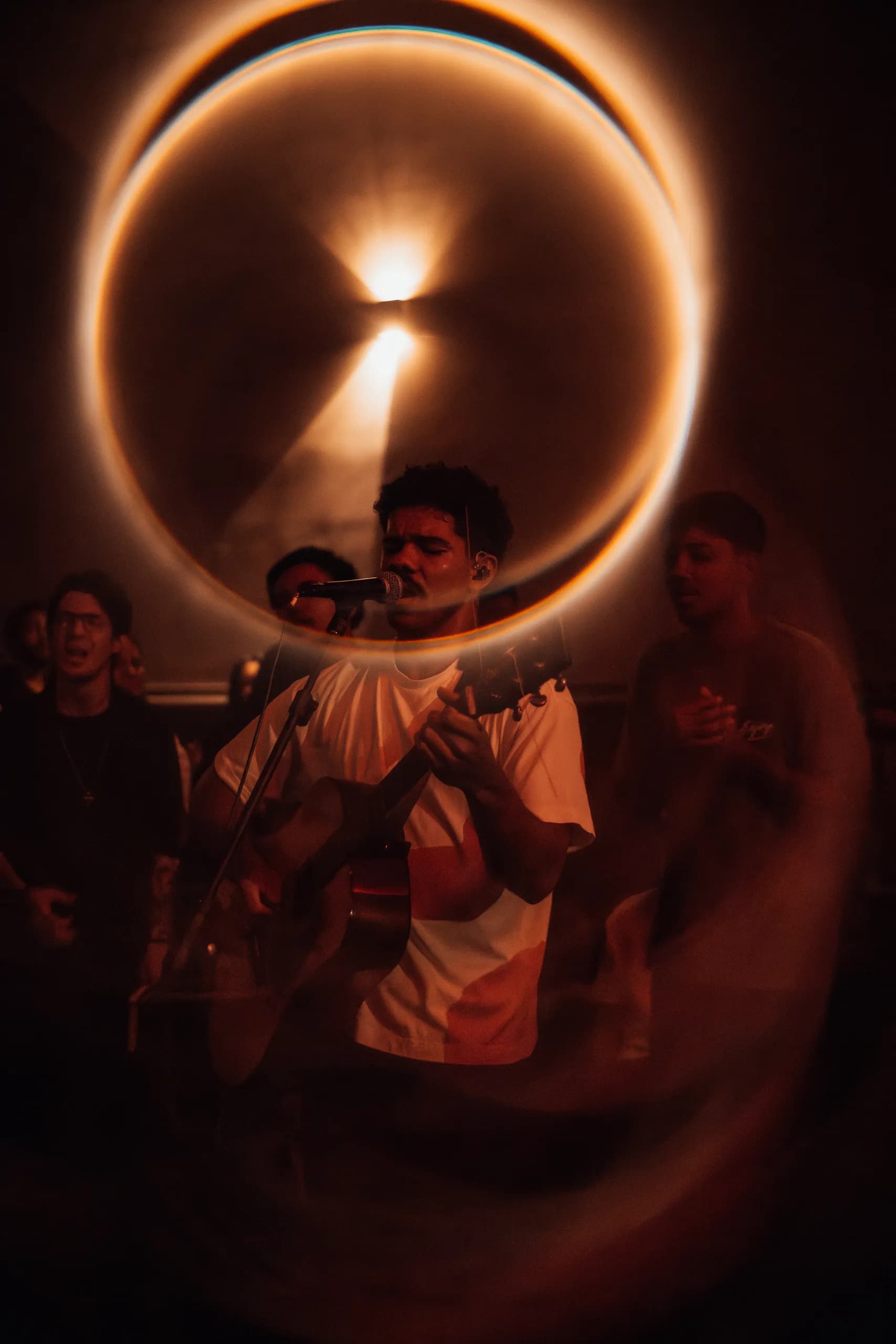 Líder de louvor cantando sob um halo de luz, em tons vermelhos